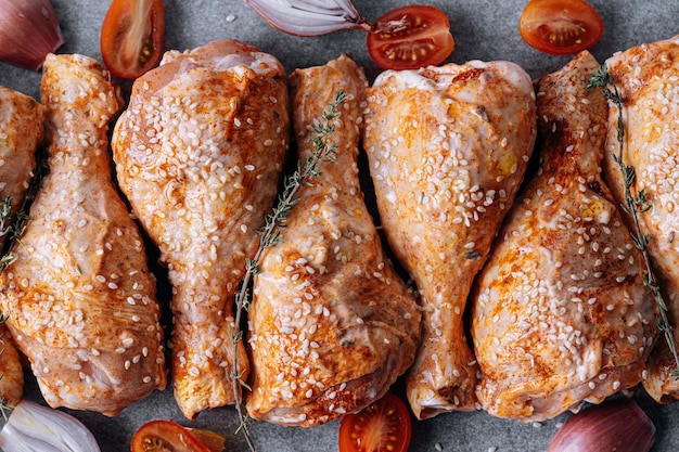 Pilons de poulet aux épices paprika et graines de sésame prêts à cuire sur une plaque à pâtisserie