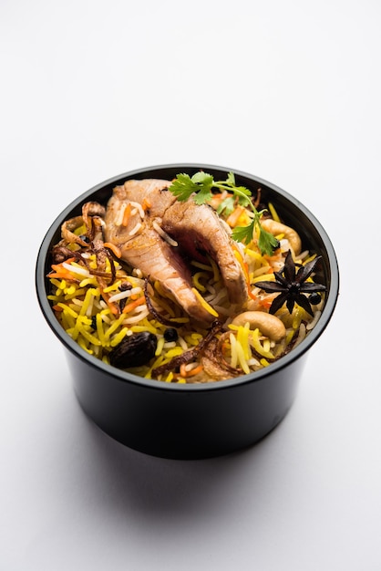 Poisson Biryani ou Pulao de style restaurant emballé pour la livraison à domicile dans une boîte ou un conteneur en plastique avec Raita et salan