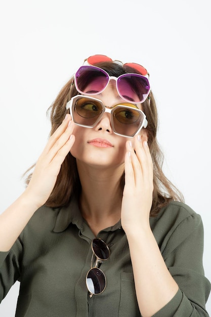 Portrait d'une belle femme portant de nombreuses lunettes de soleil sur blanc. Photo de haute qualité