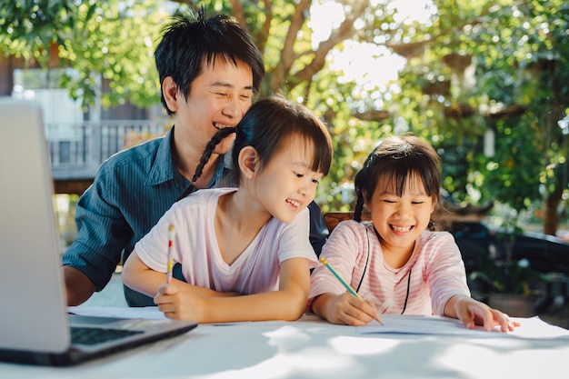 Portrait de famille du père et de la fille d'âge préscolaire utilisent un ordinateur pour étudier à la maison