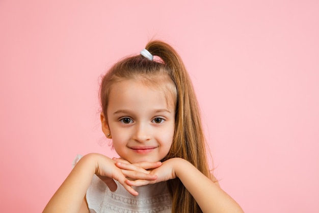 Portrait de jolie fille caucasienne isolée sur fond de studio rose avec fond