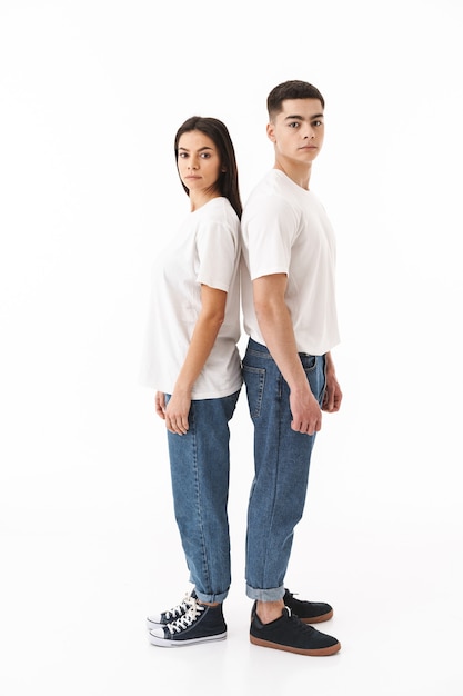 Photo portrait de toute la longueur d'un jeune couple séduisant debout dos à dos isolé sur un mur blanc