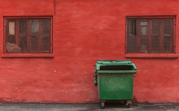 Poubelle verte sur fond de mur rouge