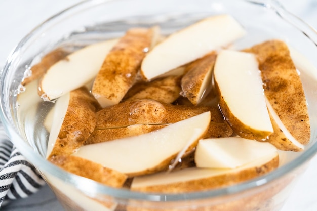 Préparation de pommes de terre russet en quartiers avec de l'huile d'olive et des épices à cuire au four