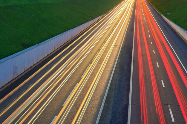 Photo route d'autoroute de nuit avec des lumières de voitures. sentier de feu jaune et rouge sur la route avec trafic de vitesse. fond urbain abstrait longue exposition