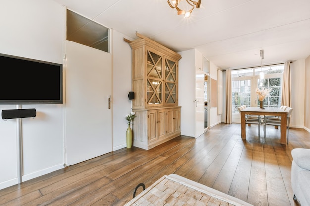 Salon spacieux avec porte d'armoire en bois et coin repas près du passage vers la cuisine aux murs beiges et parquet