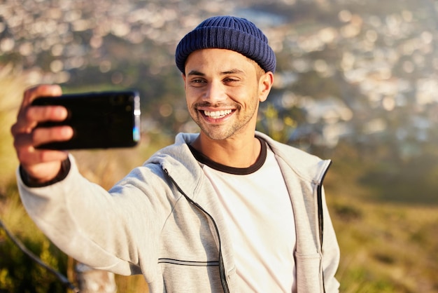 Photo selfie de remise en forme et randonnée masculine sur la montagne après avoir marché pour un exercice de bien-être dans la nature santé sportive et jeune homme randonneur prenant une photo lors d'une randonnée en plein air pour un entraînement cardio