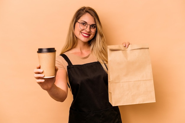 Serveur de restaurant femme caucasienne tenant un café à emporter et un sac isolé sur fond beige