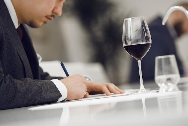 Photo sommelier évaluant le vin rouge en le dégustant et en prenant des notes sur la carte de vin du participant