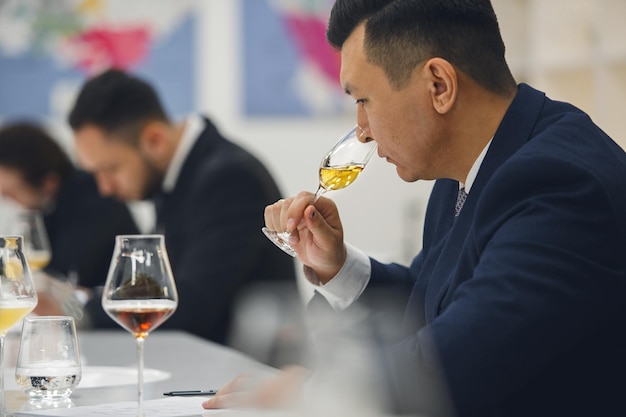 Photo sommelier professionnel reniflant du whisky inconnu lors d'une dégustation à l'aveugle