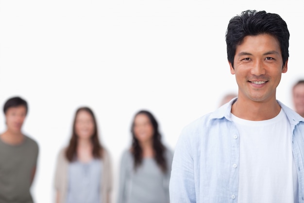 Photo souriant jeune homme avec des amis debout derrière lui sur un fond blanc