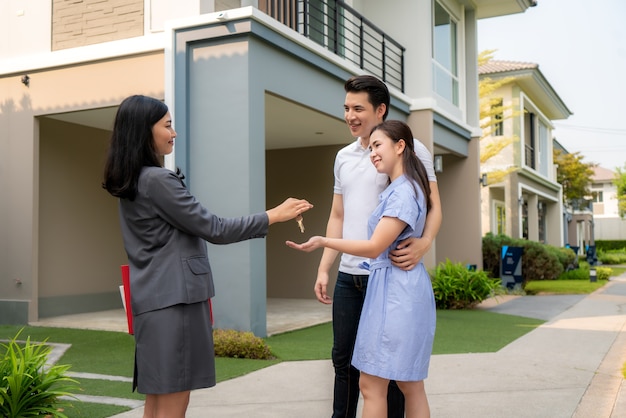 Photo sourire heureux jeune couple prendre les clés nouvelle grande maison de l'agent immobilier