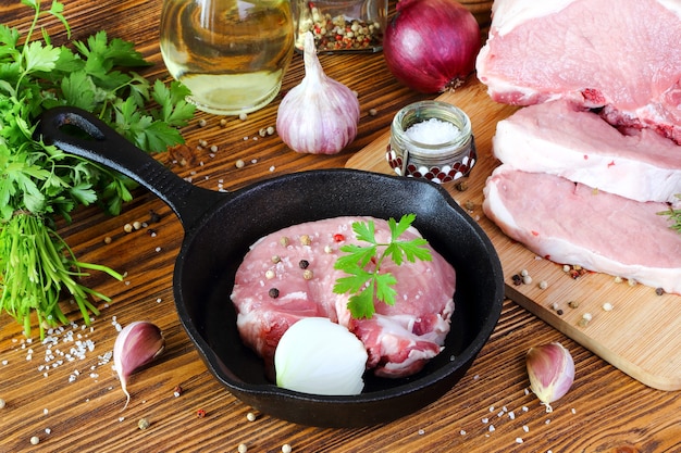 Photo steak de porc cru dans une poêle sur une table de cuisine