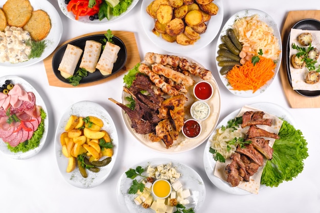 Une table couverte avec de nombreux plats différents pour le dîner. Beaucoup de nourriture sur un fond blanc isolé.