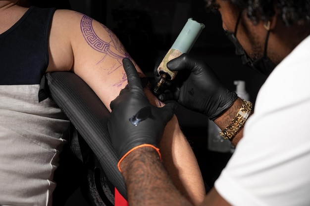 Un tatoueur professionnel afro-américain fait un tatouage sur le bras du client