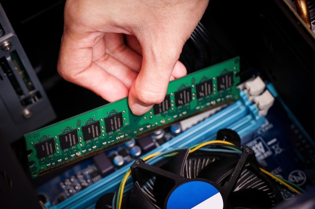 Un technicien en informatique installe une nouvelle mémoire RAM DDR (mémoire à accès aléatoire) dans un PC.