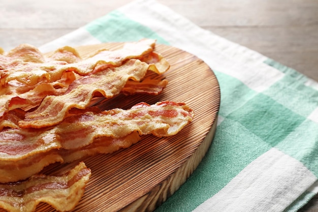 Photo tranches de bacon frit sur planche de bois