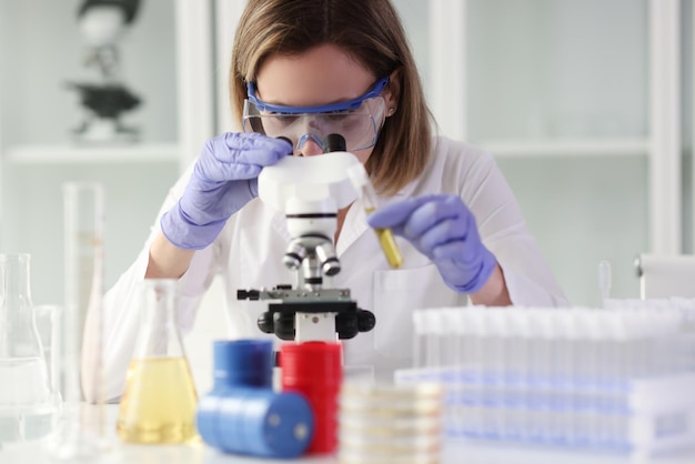 Le travailleur de laboratoire examine des échantillons de substances sous détection au microscope de maladies de