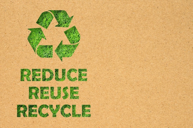 Trou de papier kraft de réutiliser réduire recycler le symbole et le texte sur fond d'herbe verte