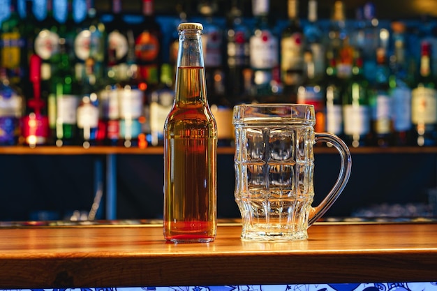 Verre à bière et bouteille sur un comptoir en bois dans un pub