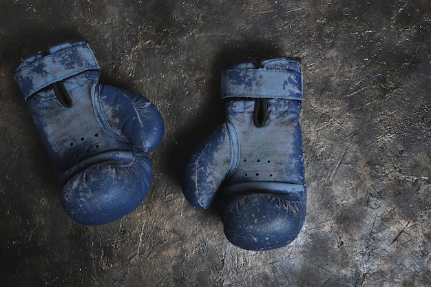 De vieux gants de boxe bleus sur un fond de béton