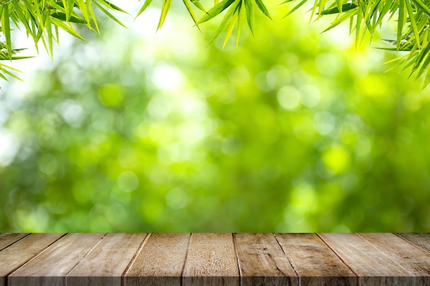 Vieux plateau de table en bois vide avec cadre de feuilles de bambou sur fond de verdure floue dans le jardin