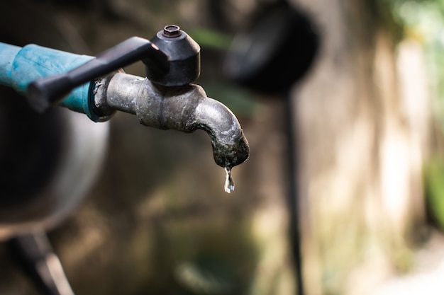 Un vieux robinet avec de l'eau qui fuit tombe au sol.