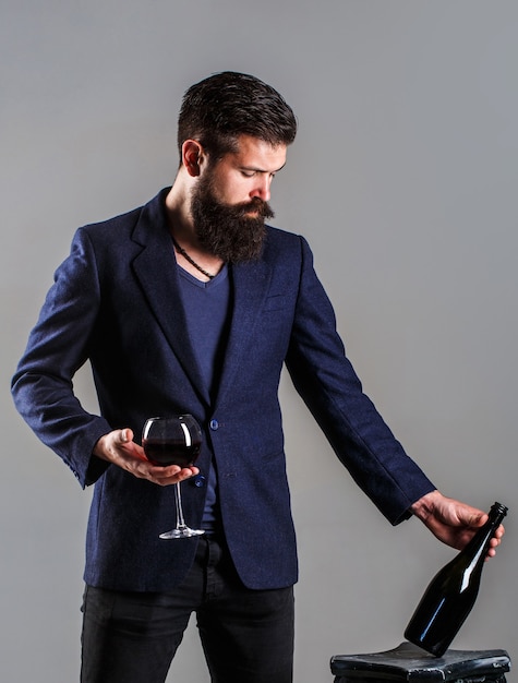 Photo vin rouge en bouteille, verre à vin. homme sommelier, dégustateur, cave.