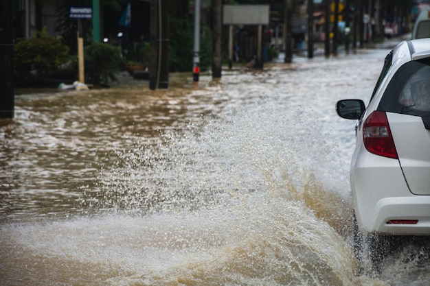 Voiture roulant sur route inondée avec écoulement d'eau d'inondation à travers la route après de fortes pluies et des ondes de tempête