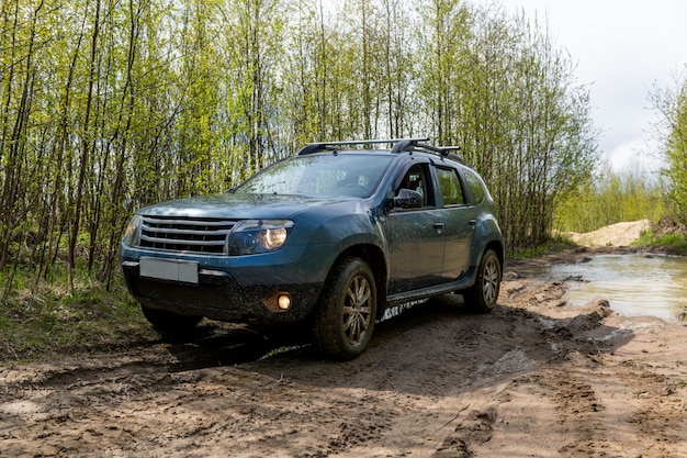 Voiture sale sur route boueuse dans une forêt.