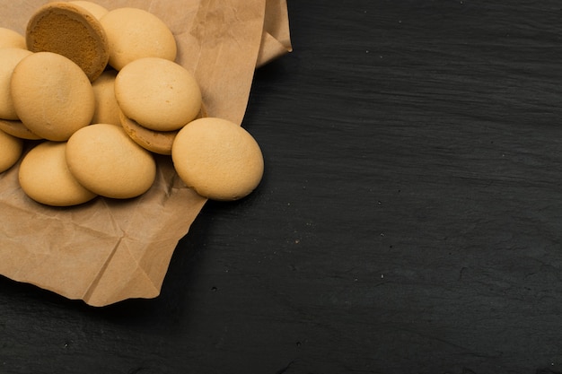 Vue de dessus de biscuits maison ronds sur fond sombre. Biscuits renversés avec du papier d'emballage