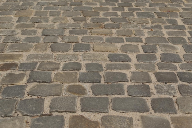 Vue de dessus de la chaussée ancienne grise ou route pavée de granit. Sol pavé de briques anciennes ou rue de carreaux de granit avec de grosses pierres