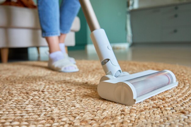 Photo vue rapprochée de l'aspirateur nettoyant le tapis au pinceau sur le sol