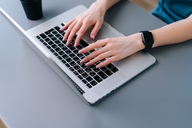 Vue rapprochée de dessus des mains d'une femme d'affaires méconnaissable tapant sur un clavier d'ordinateur portable assis au bureau