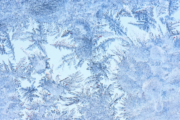 Photo abstract ice background, blue background with cracks on the ice surface. copy space, natural texture, macro. frosty pattern on the winter window glass