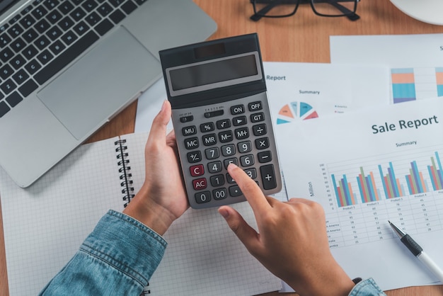 The accountant's hand is using the calculator. For cost analysis Profit and loss and tax calculation concept preparation of financial statements