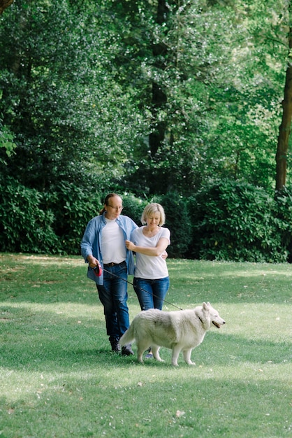 Adult couple walking on the grass with a white dog