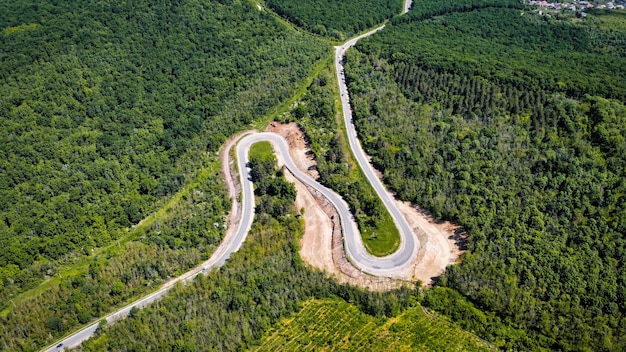 Aerial drone view of a village in Moldova. Winding road passing through a lush forest