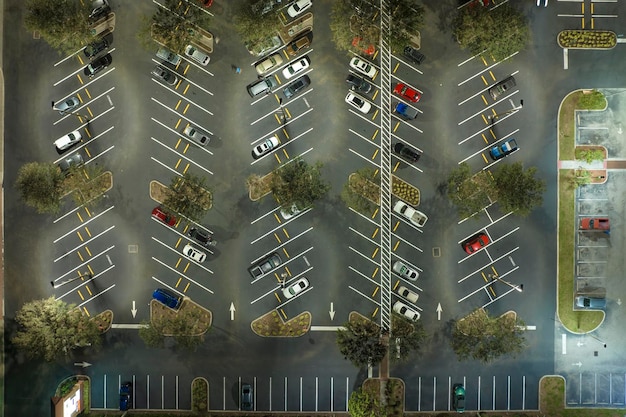 Aerial night view of many cars parked on parking lot with lines and markings for parking places and directions Place for vehicles in front of a grocery mall store