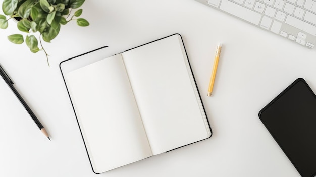 Photo aerial shot of an open notebook pencil and a potted plant on a white desk featuring a simple and elegant workspace setup