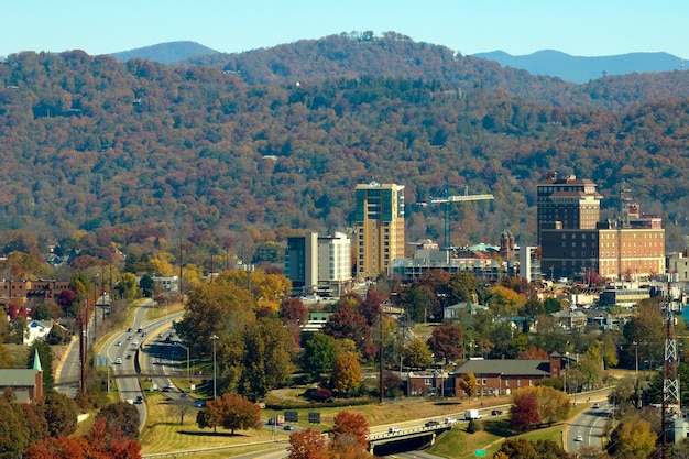 Aerial view of Asheville city in North Carolina with high buildings and mountain hills in distance