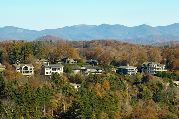 Aerial view of big family houses on mountain top between yellow trees in North Carolina suburban area in fall season Real estate development in american suburbs