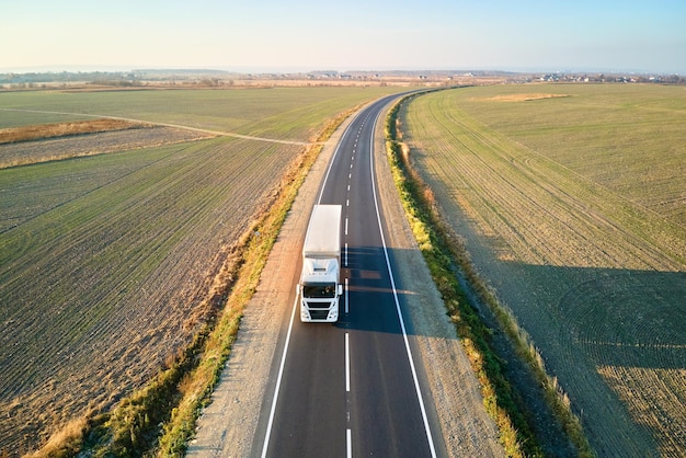 Aerial view of blurred fast moving semitruck with cargo trailer driving on highway hauling goods in evening Delivery transportation and logistics concept