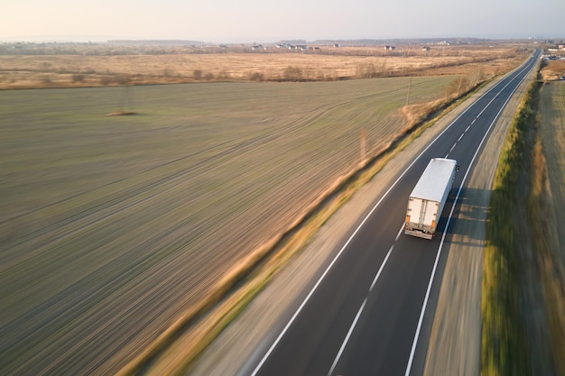 Aerial view of blurred fast moving semitruck with cargo trailer driving on highway hauling goods in evening Delivery transportation and logistics concept