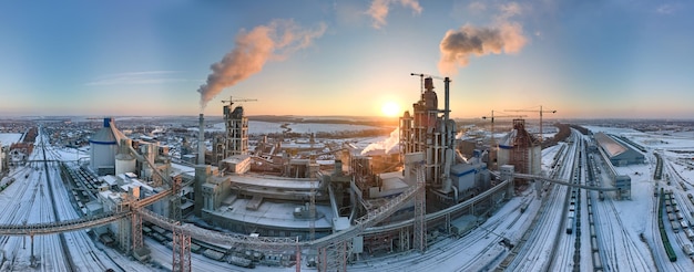 Aerial view of cement factory with high concrete plant structure and tower crane at industrial production area in evening Manufacture and global industry concept