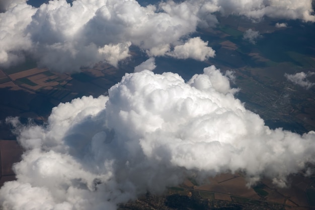 Photo aerial view from airplane window of white puffy clouds on bright sunny day.