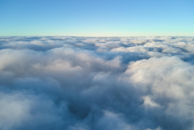 Aerial view from above at high altitude of dense puffy cumulus clouds flying in evening Amazing sunset from airplane window point of view