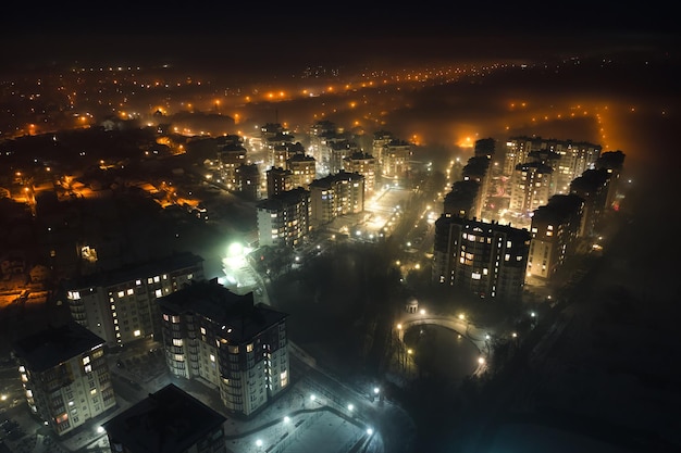 Aerial view of high rise apartment buildings and bright illuminated streets in city residential area at night Dark urban landscape