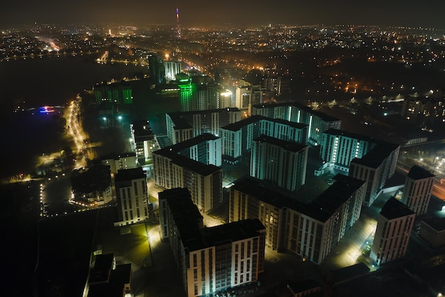 Aerial view of high rise apartment buildings and bright illuminated streets in IvanoFrankivsk city Ukraine residential area at night Dark urban landscape