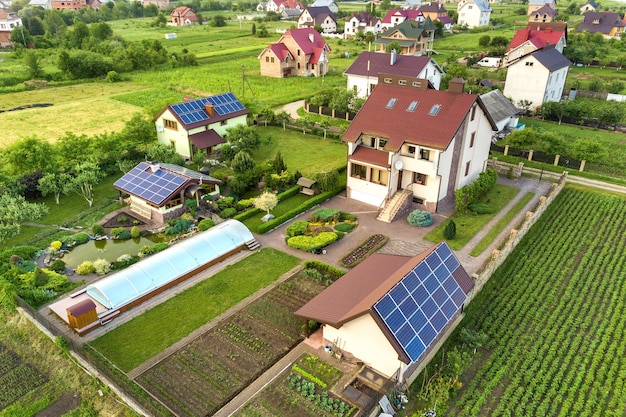 Aerial view of a private house in summer with blue solar photo voltaic panels on roof top and green yard